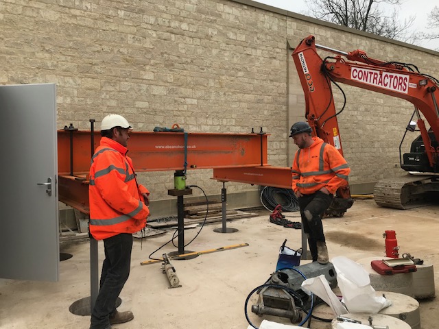 Contractors lifting a steel beam into place with an excavator