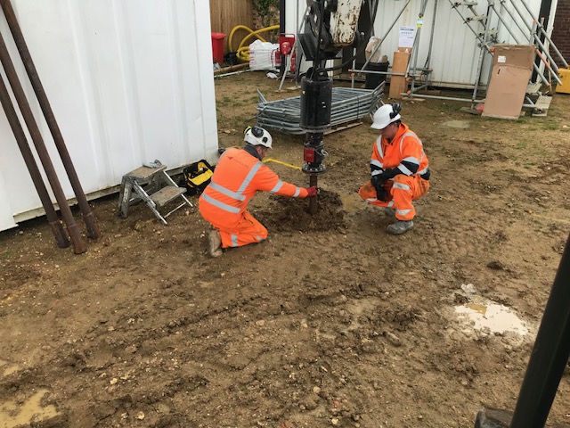 Engineers installing a ground anchor drilling rig on site